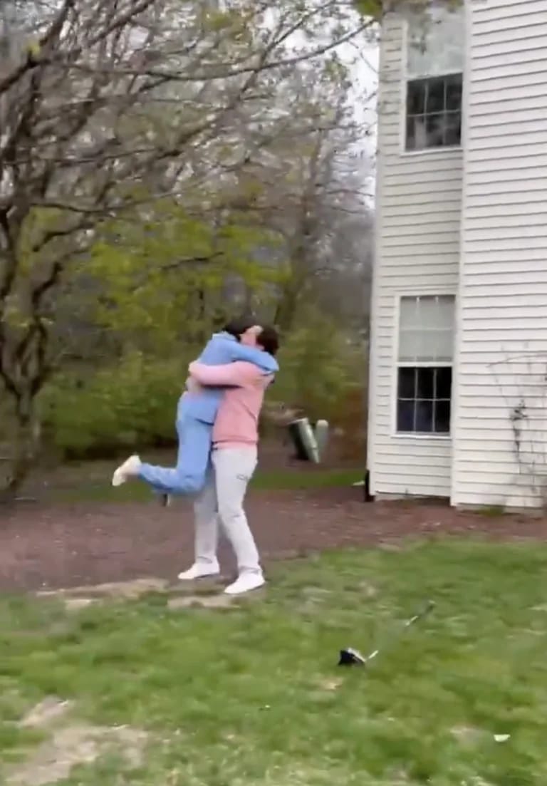 Couple embracing and celebrating in a backyard after a gender reveal moment